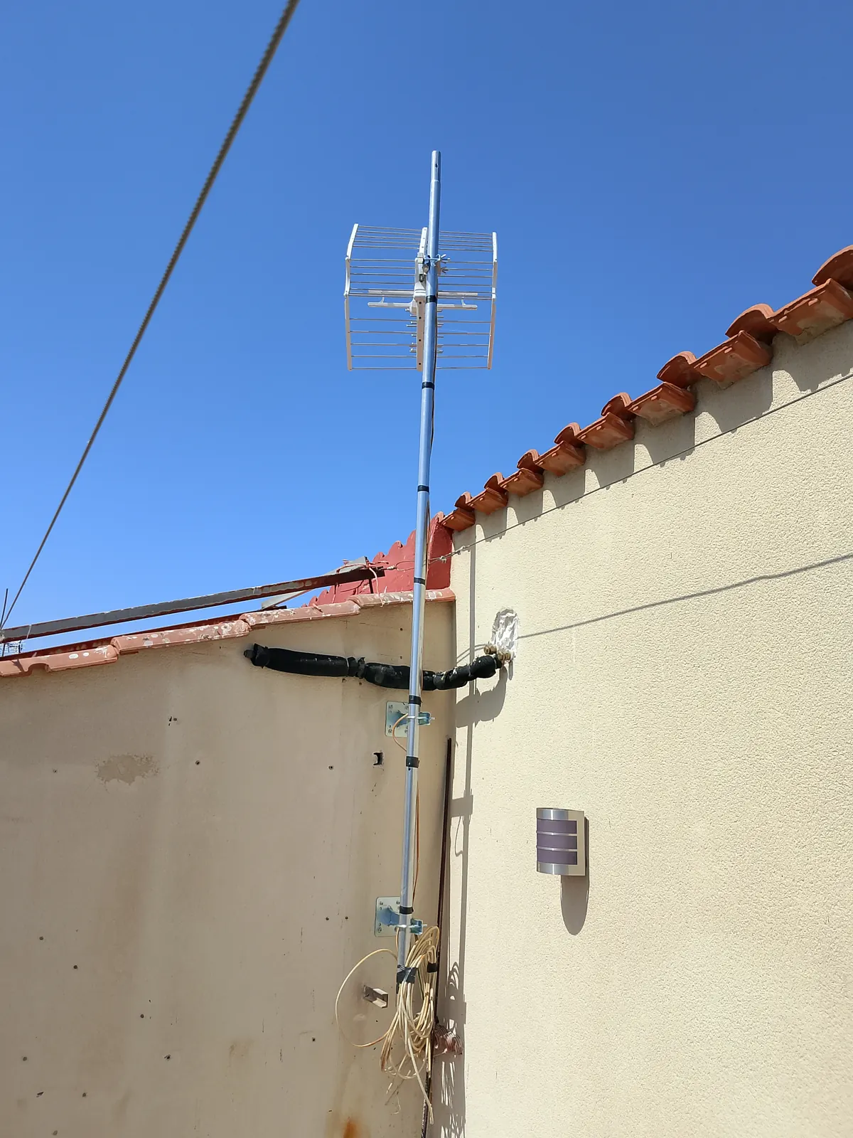 Màstil d’antena fixat a la façana.
