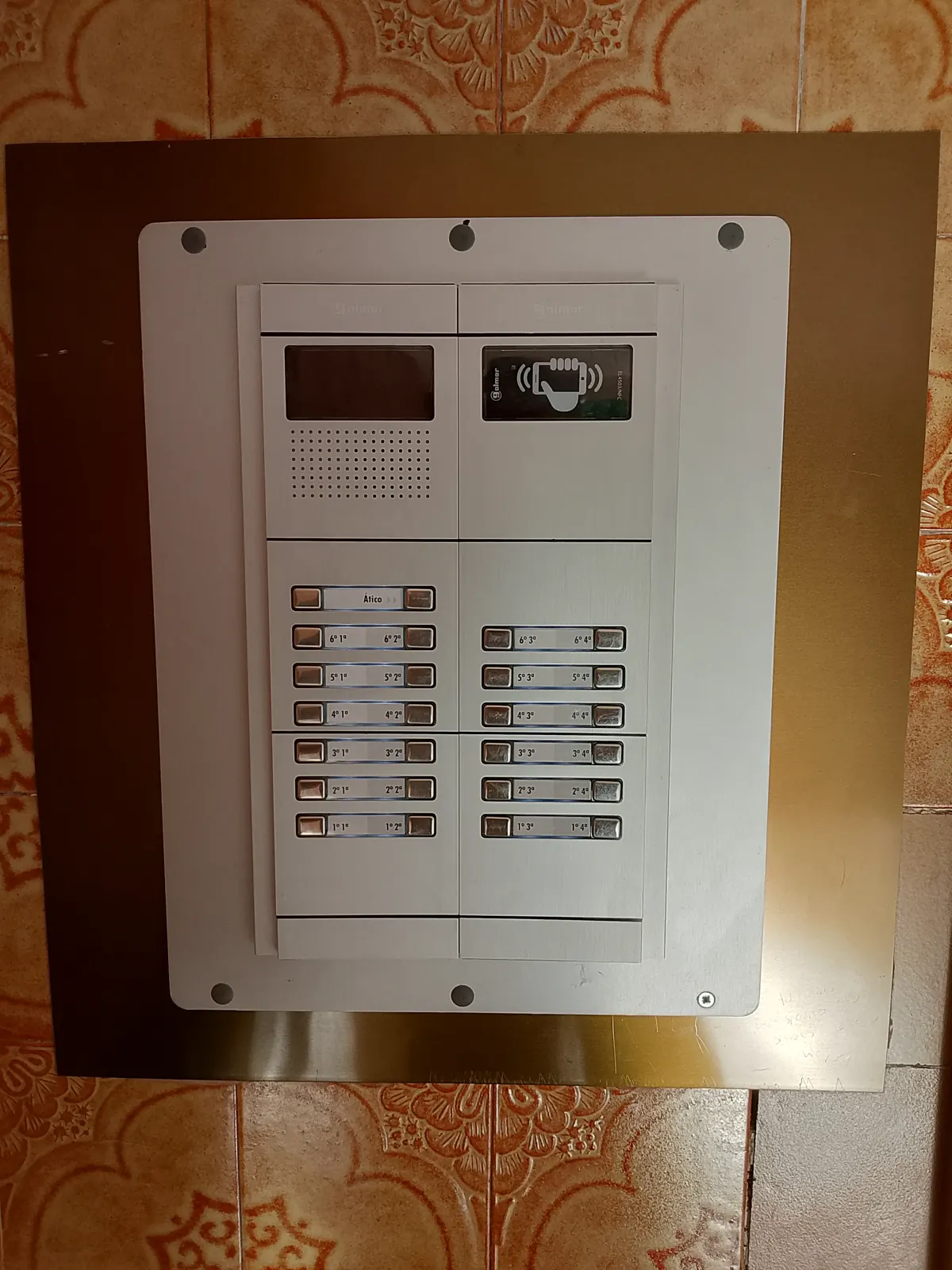 Placa de videoporter amb pantalla i botonera en una comunitat de veïns.